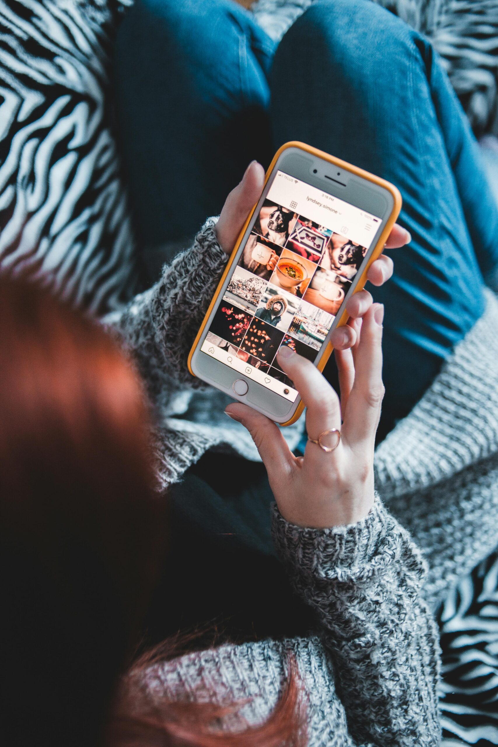 Woman scrolling through social media on smartphone, cozy setting.